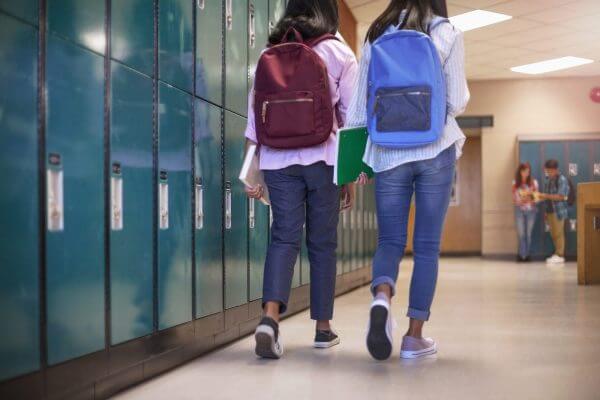 A photo of two students walking down a school hallway together.
