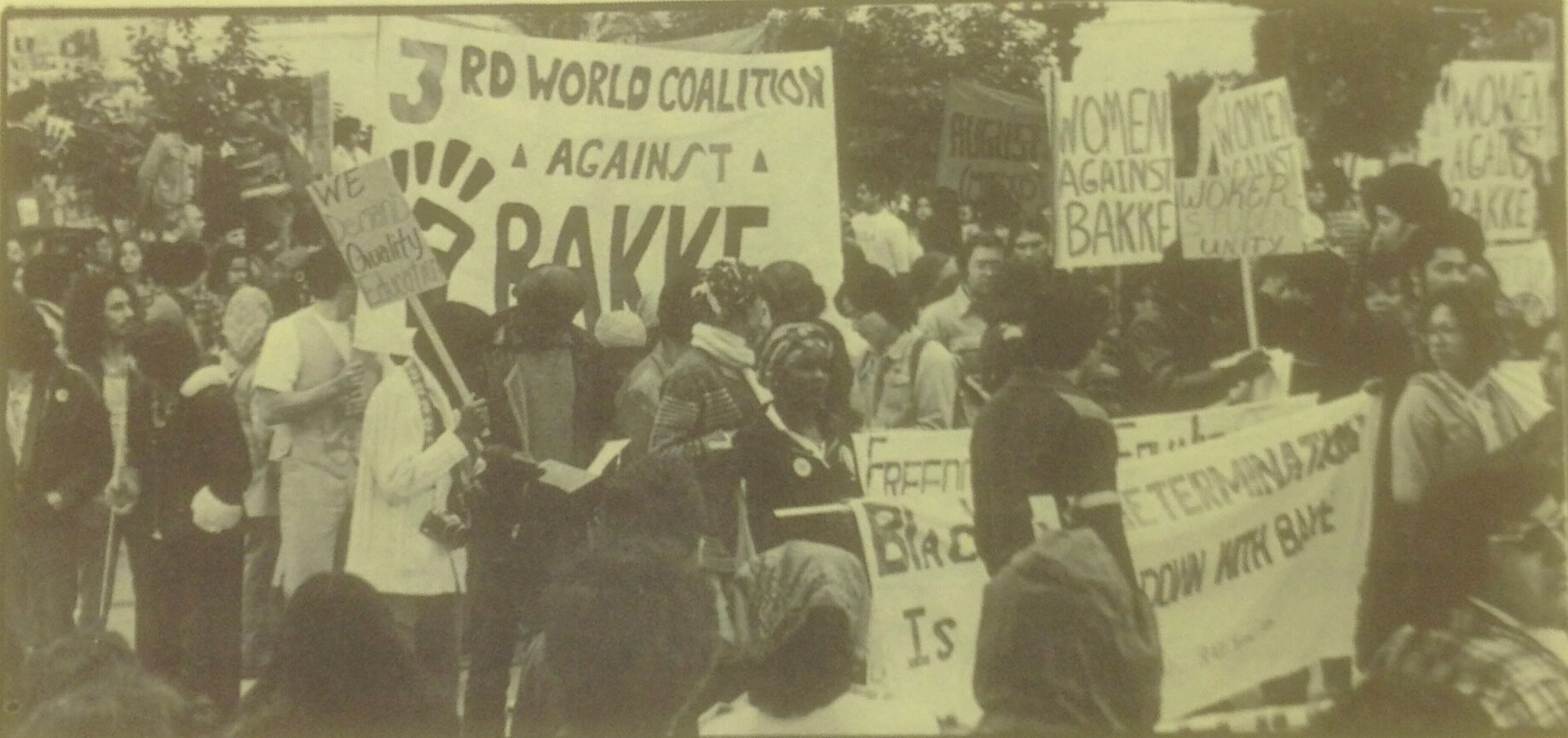 A crowd of protestors holding signs to denounce Bakke. Some signs read "we deserve quality education" and "women against Bakke."